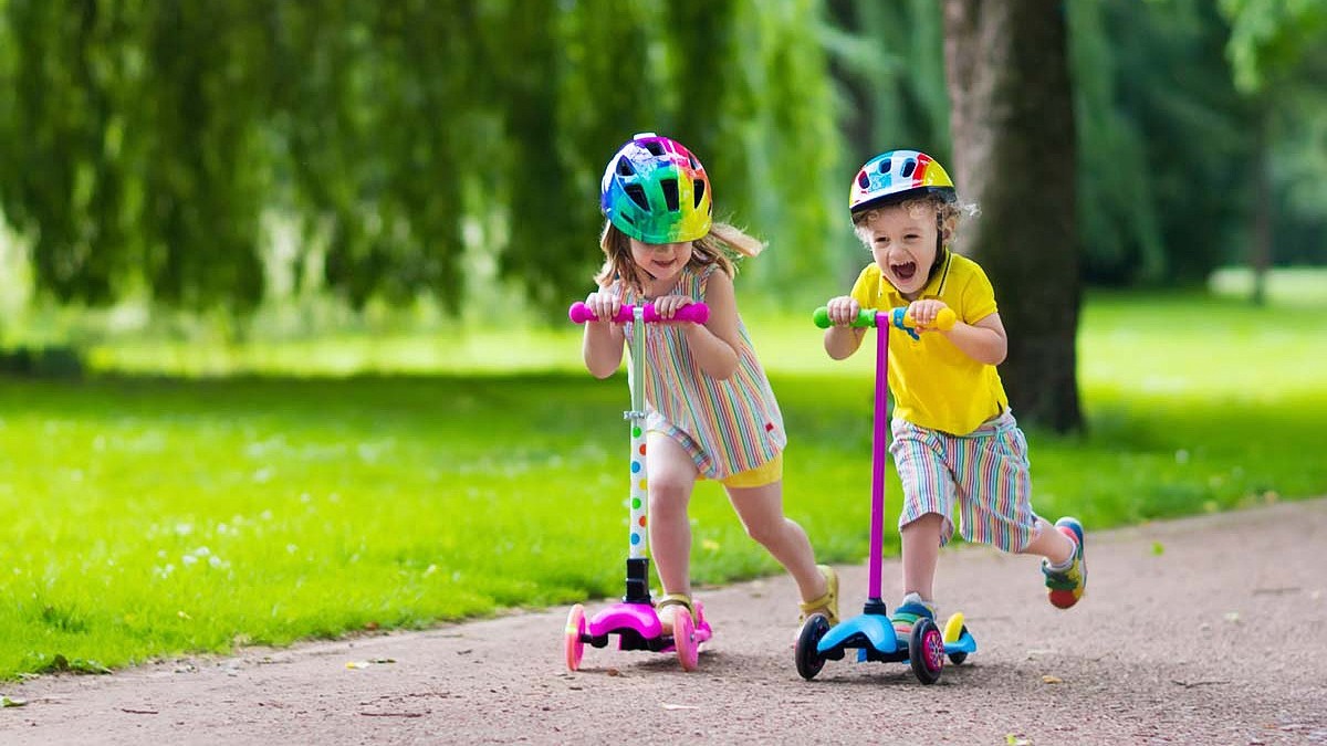Children learn to ride scooter in a park