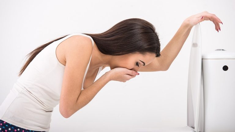 Young woman vomiting into the toilet bowl
